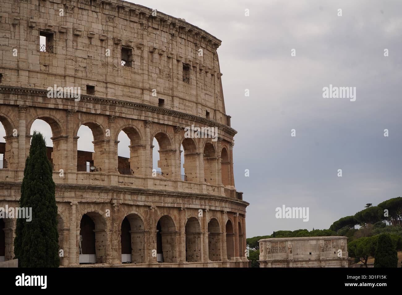 La facciata dettagliata del Colosseo contro un cielo nuvoloso. Cattura la scala storica, il decadimento e la grandezza di questo iconico monumento in tranquillità. Foto Stock