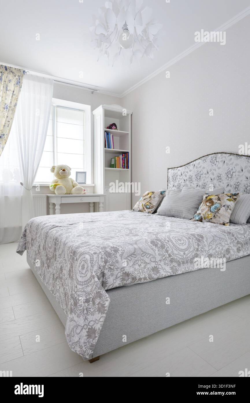 Elegante camera da letto in colori tenui e chiari, grande letto al centro Foto Stock