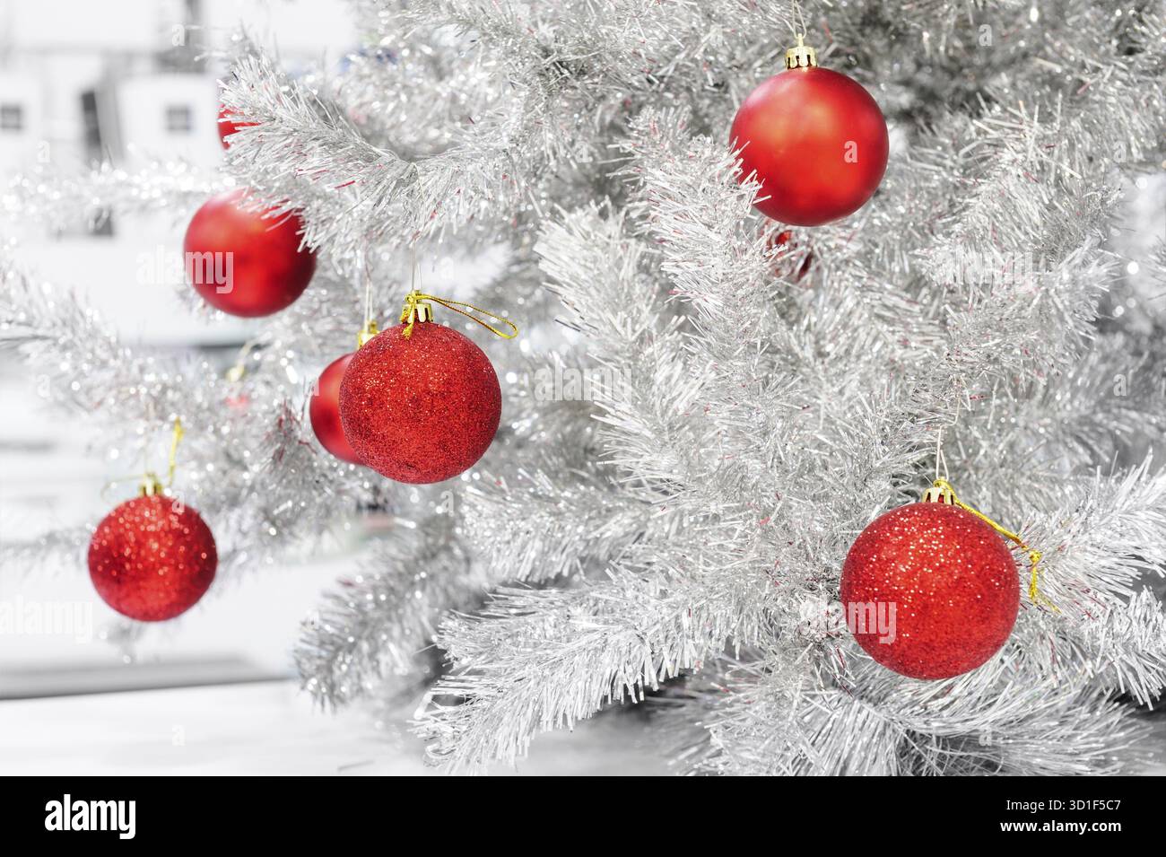 Red baubles appeso su argento albero di Natale artificiale, buono come sfondo Foto Stock