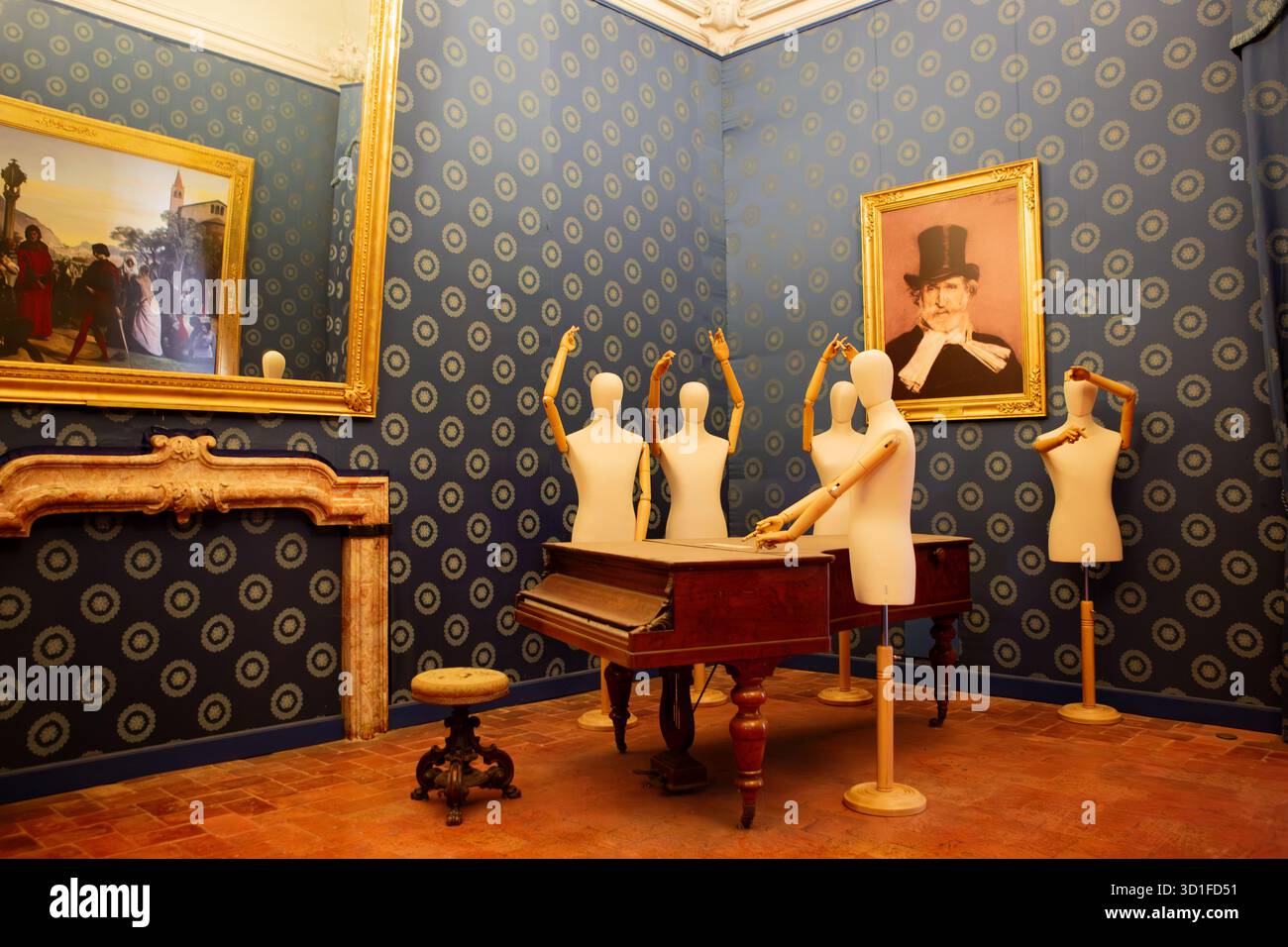 Un'installazione artistica surreale mostra manichini di legno intorno ad un pianoforte antico in una stanza in stile vintage con carta da parati a motivi geometrici. Foto Stock