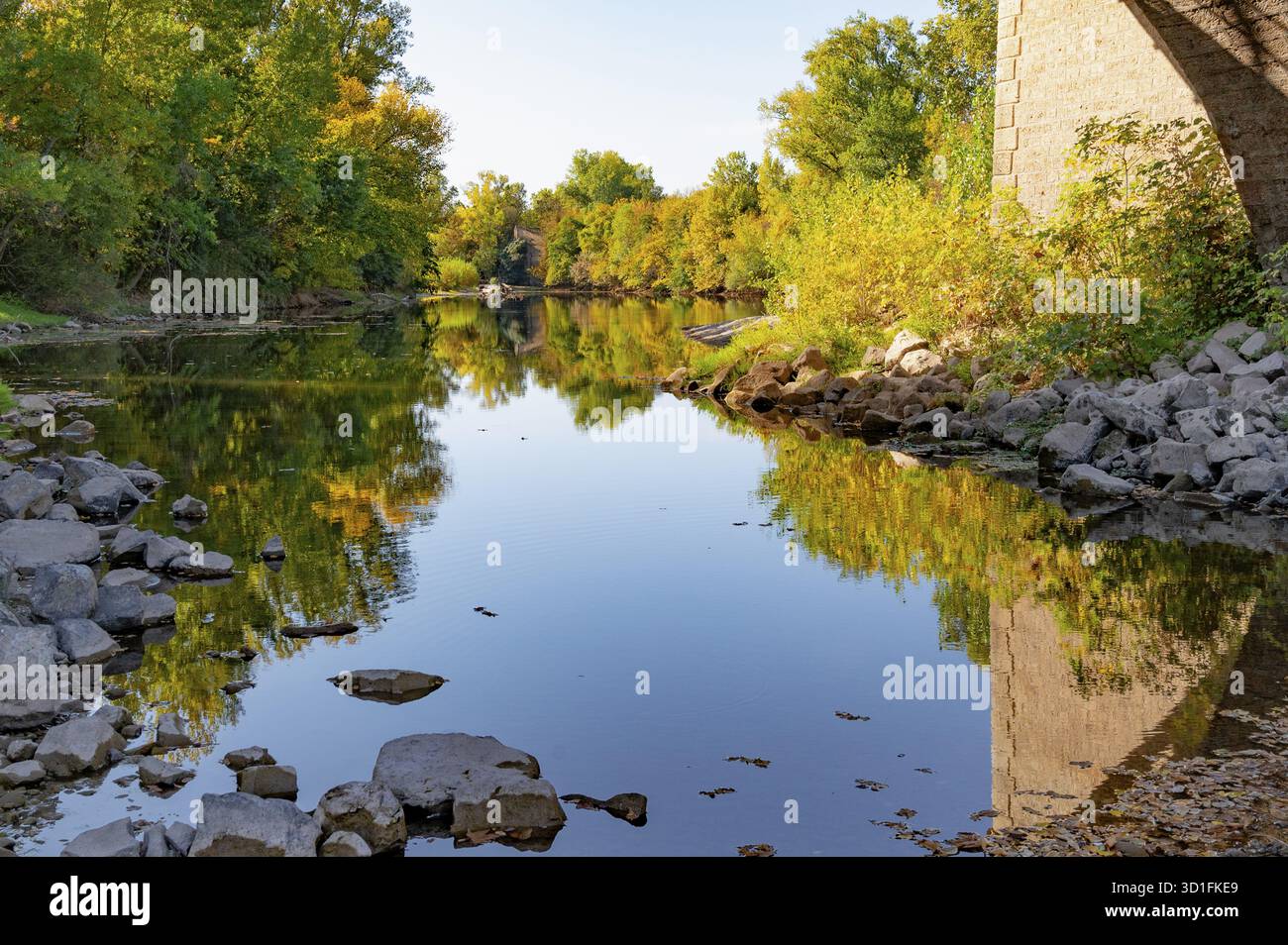 Sezione del fiume Herault con acqua blu scuro, incorniciata da fitte foreste ripariali, il cui fogliame brilla in brillanti sfumature autunnali dal giallo all'ulivo Foto Stock