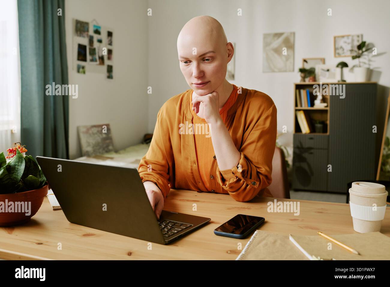 Ritratto di una giovane donna adulta con Alopecia concentrata sullo schermo di un notebook Foto Stock