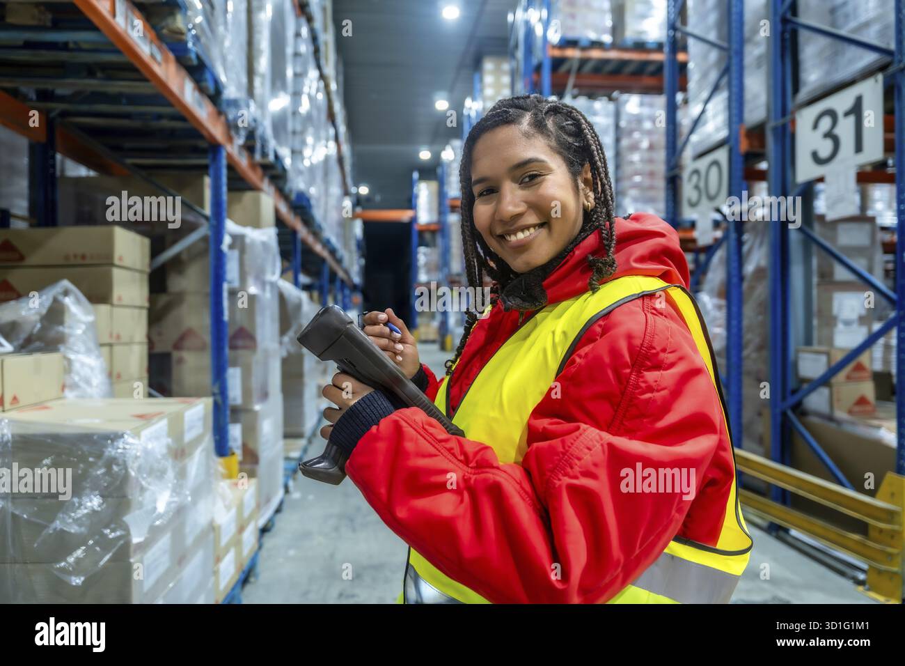 Il magazziniere dell'america Latina sorride mentre utilizza uno scanner di codici a barre per eseguire controlli dell'inventario e gestire la logistica della catena del freddo in un ambiente refrigerato Foto Stock