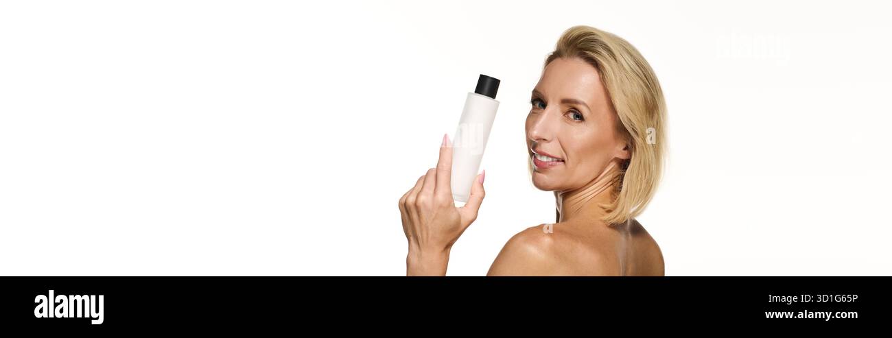 Una donna bionda sorridente con capelli corti promuove la pelle sana con un prodotto per la cura della pelle, striscione Foto Stock