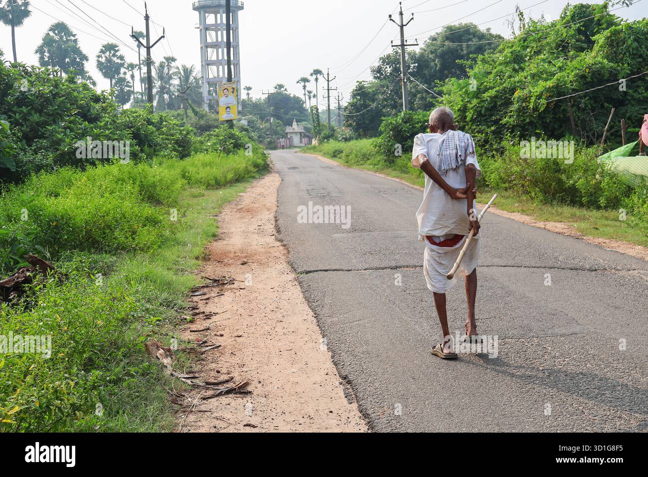 Bheemili, Visakhapatnam, Andhrapradesh - 10 settembre 2025: Un vecchio che cammina su una strada del villaggio tenendo in mano un bastone. Vecchio indiano. Foto Stock