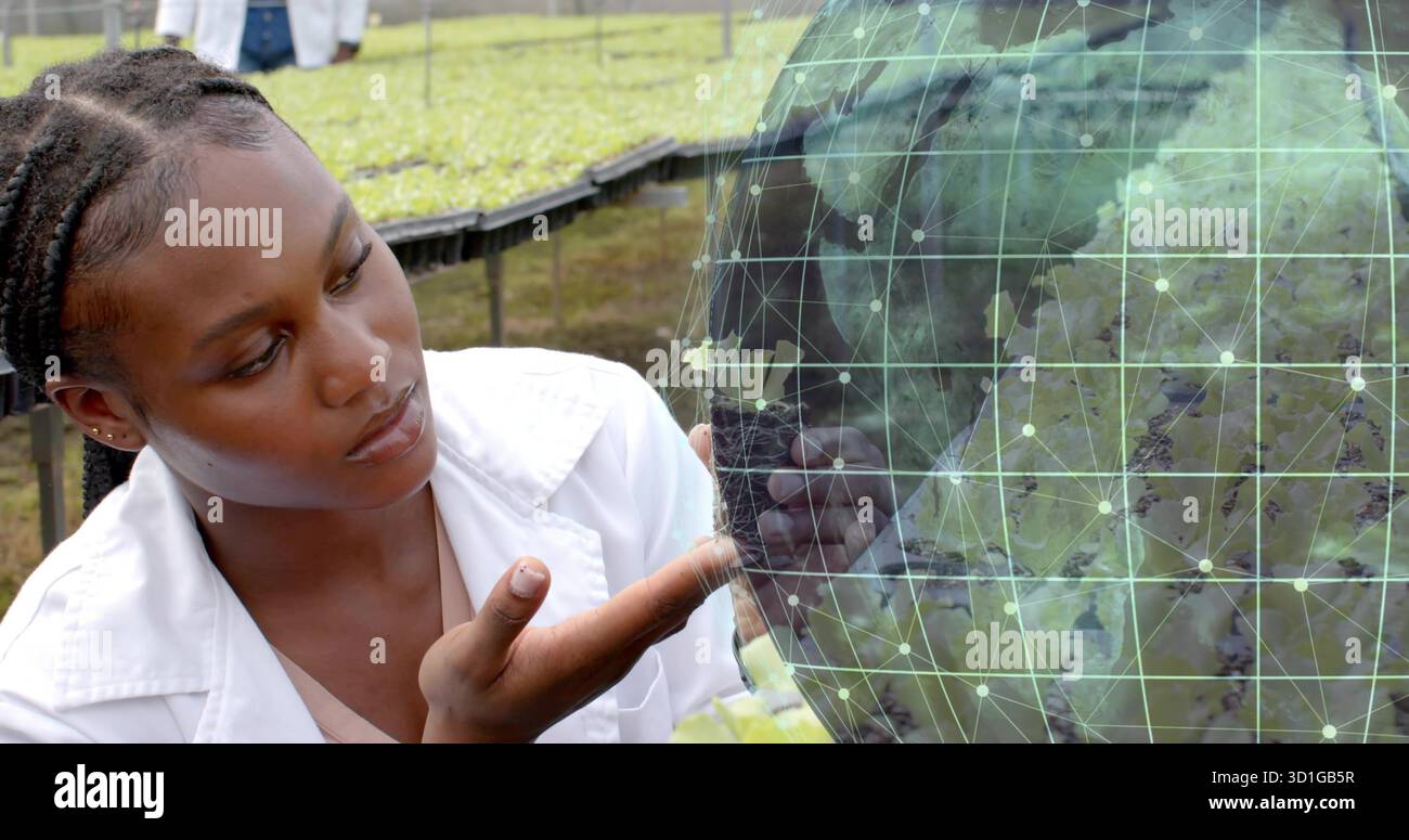 Scienziato accovacciato che esamina la sovrapposizione del globo digitale su un terreno erboso con vassoi per piantine, spazio di copia Foto Stock