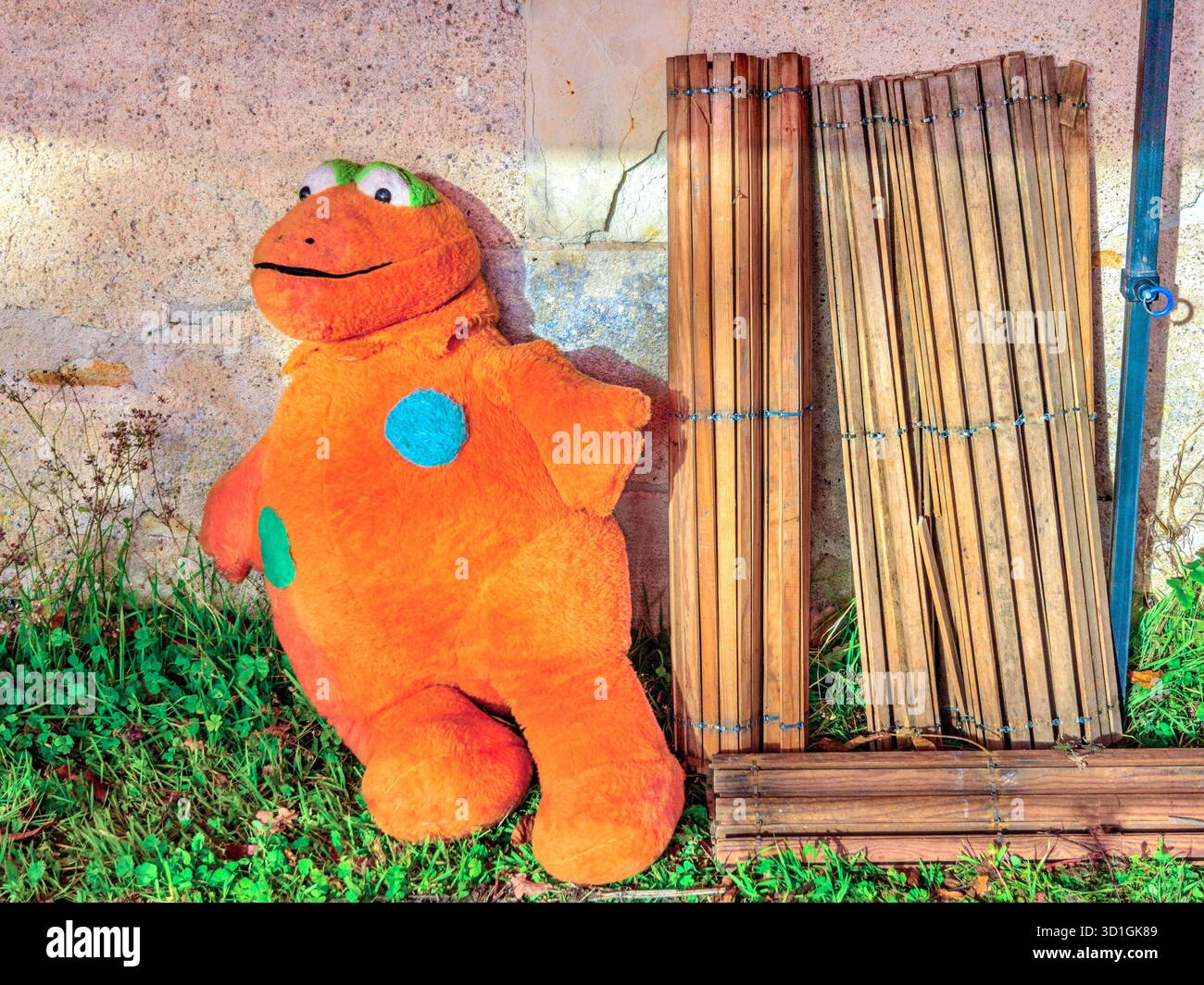 Strano giocattolo di animali ripieni di arancio brillante accanto alle vecchie finestre in legno in vendita presso il brocante/garage di vendita - Francia centrale. Foto Stock