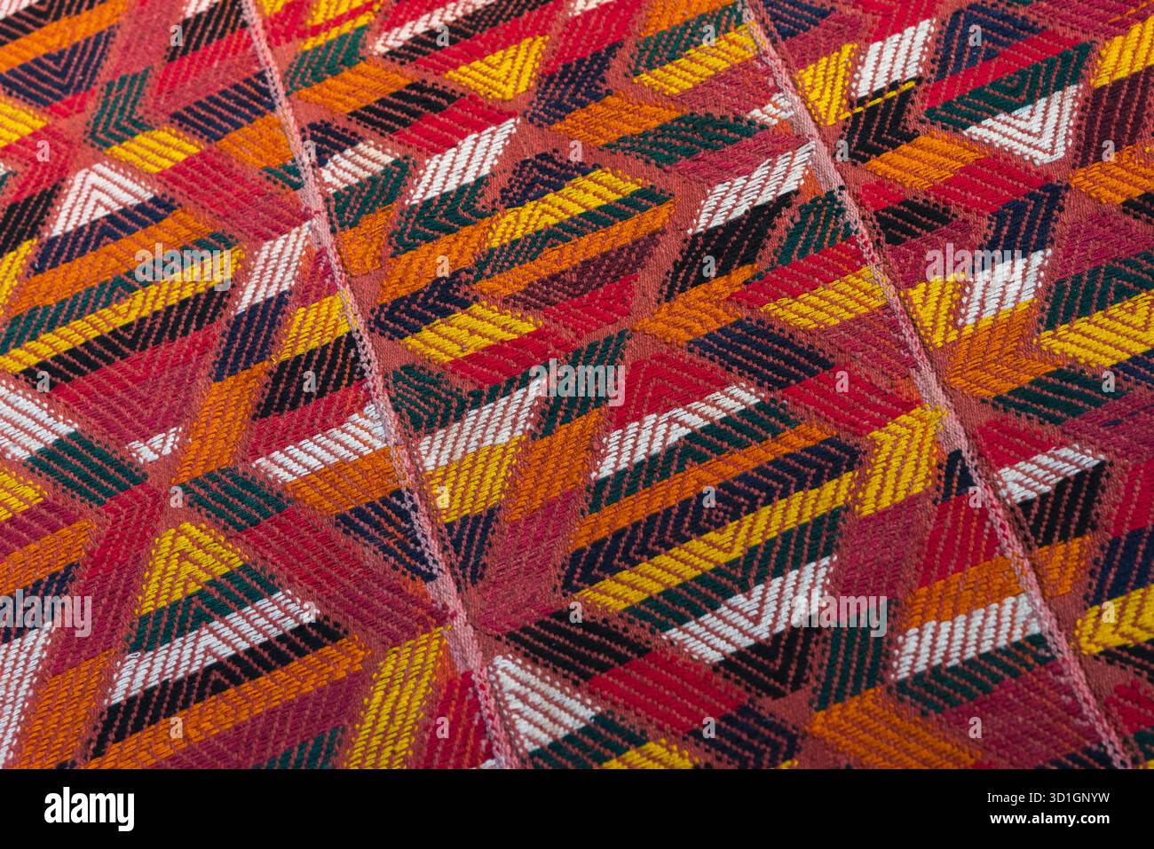 Un vivace tappeto arabo intrecciato a mano con motivi ripetuti, rosso brillante, giallo e bianco, texture fotografica di sfondo Foto Stock