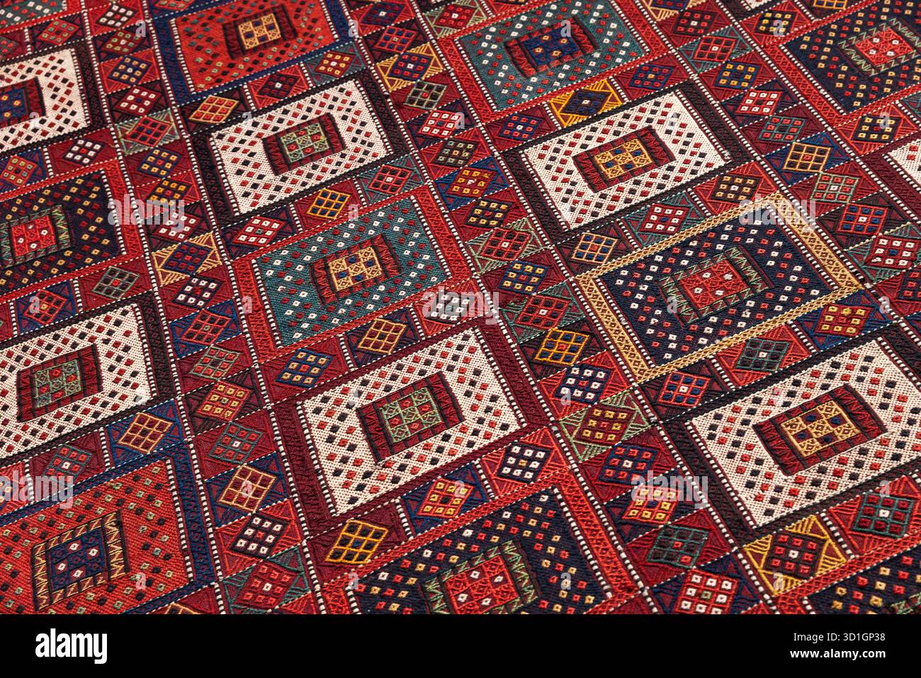 Vivace tappeto in tessuto orientale caratterizzato da audaci diamanti e quadrati colorati. I ricchi motivi geometrici creano un'atmosfera calda e artistica, ideale per arredare la casa Foto Stock