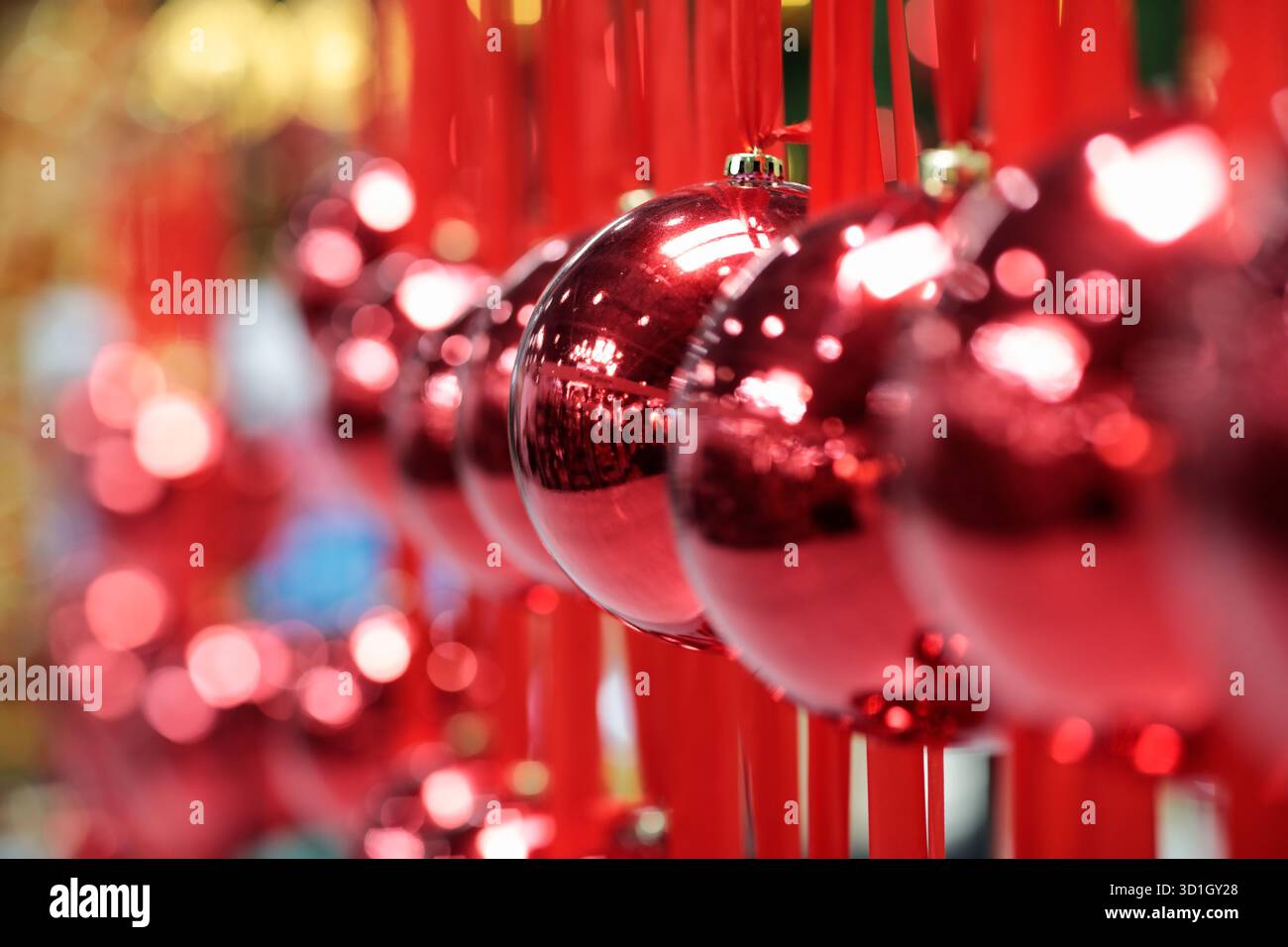 Grandi palle di Natale appese su nastri rossi. Decorazioni di Natale e Capodanno. Messa a fuoco selettiva. Foto Stock