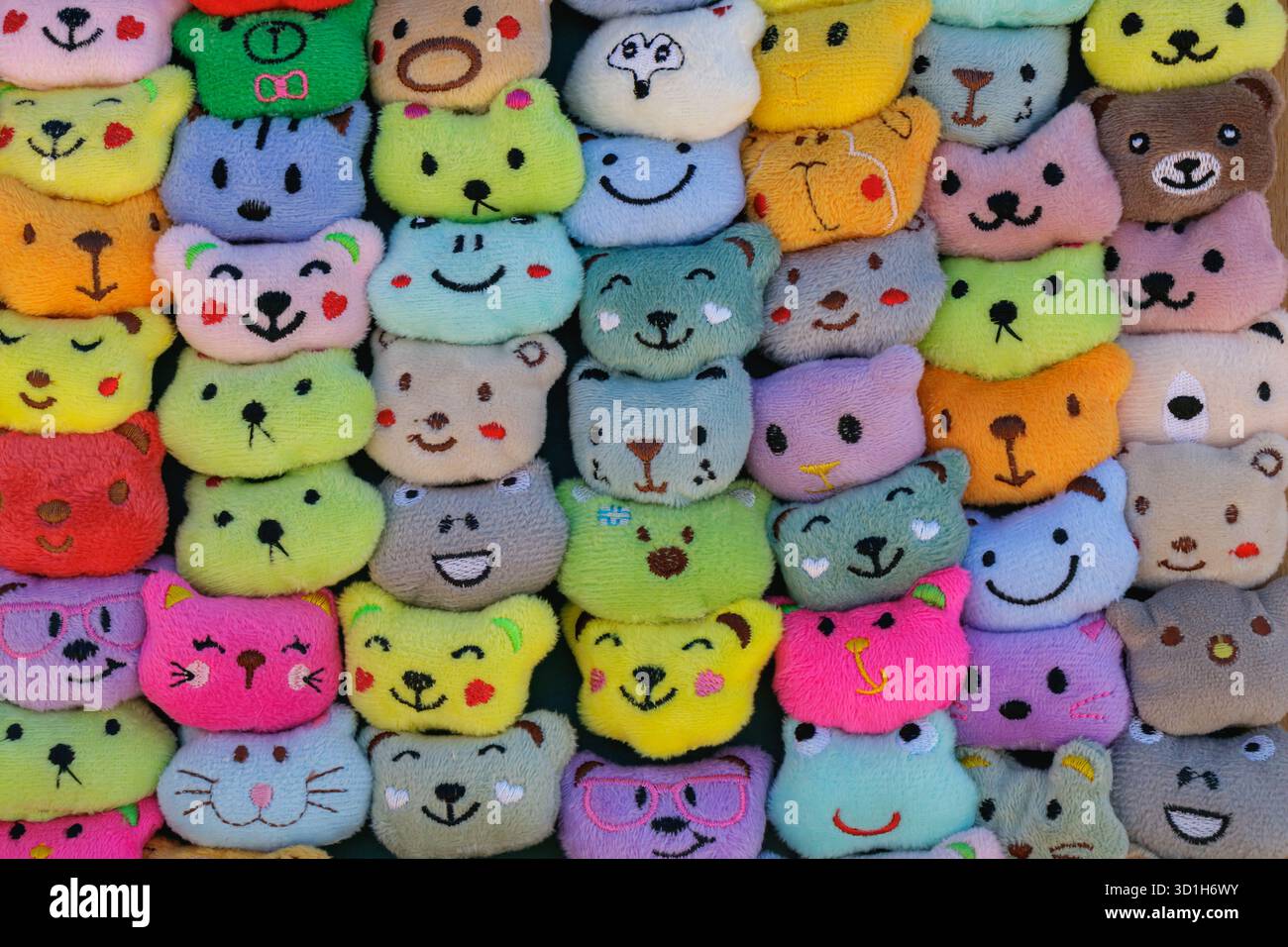 Una vibrante collezione di giocattoli di animali ripieni fatti a mano esposti in un bancone del mercato. I colori giocosi, le diverse espressioni e le texture morbide creano un Foto Stock