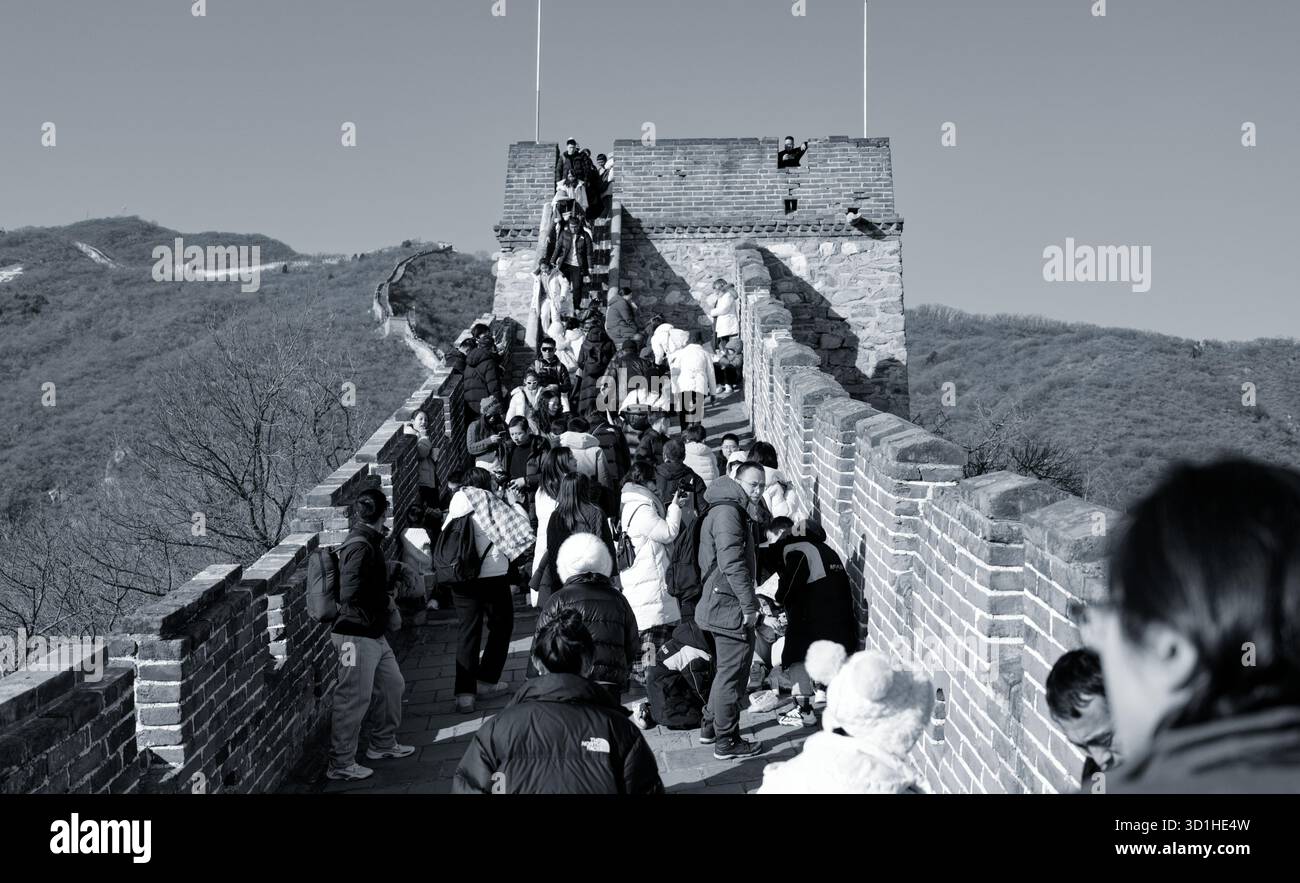Ripide scalinate di pietra piene di turisti che si radunano vicino a una torre di guardia sotto il sole invernale sulla grande Muraglia Foto Stock