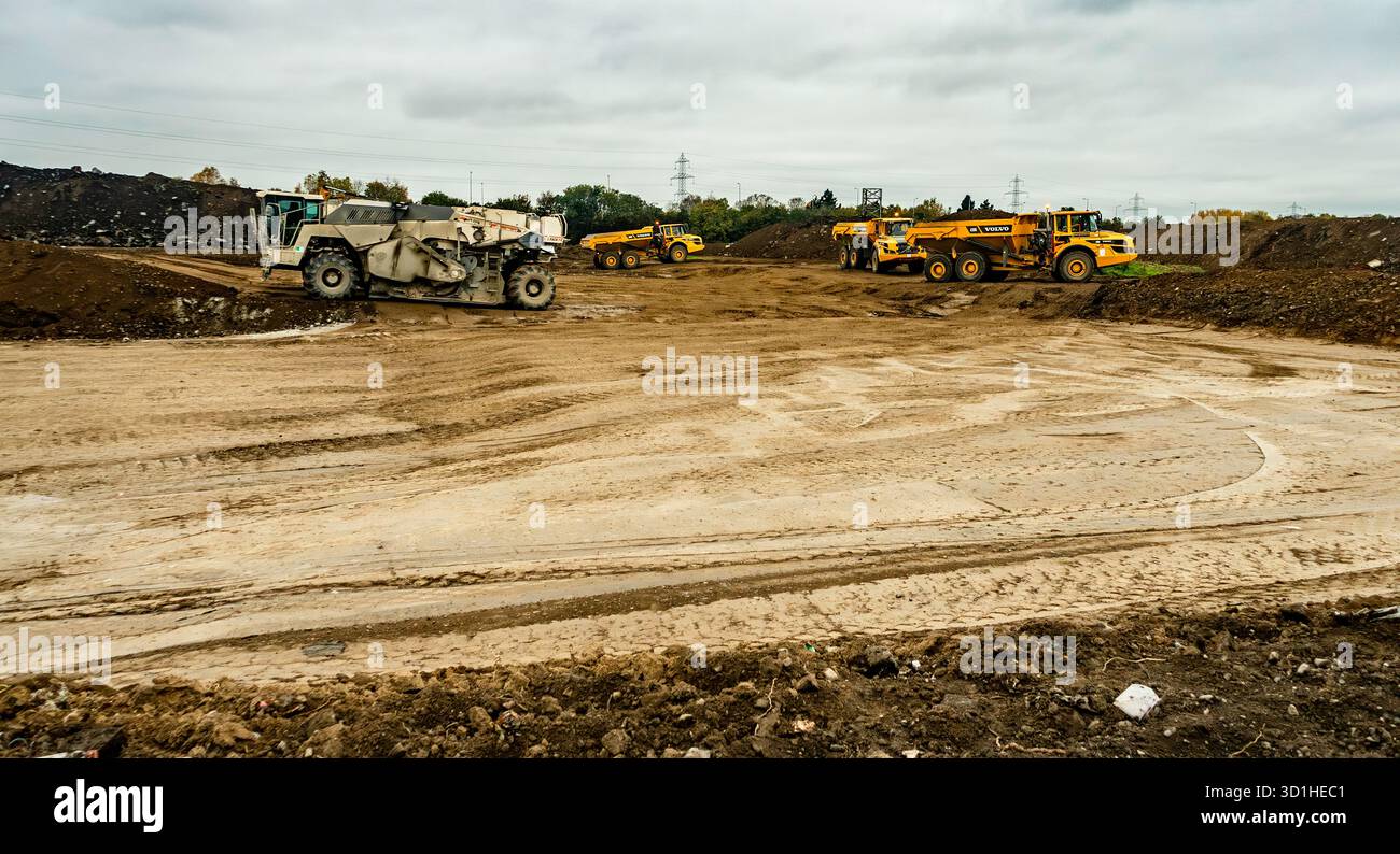 Cantiere a Dublino, Irlanda, con macchinari pesanti, dumper e traslocatori di terra che preparano il terreno per lo sviluppo sotto cieli nuvolosi. Foto Stock