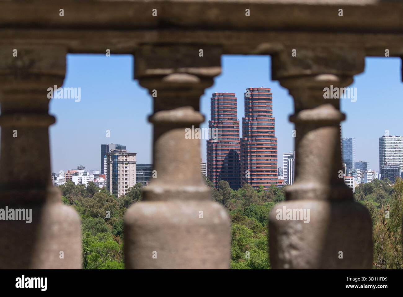 Le moderne torri gemelle rosse si vedono attraverso la storica balaustra in pietra nello skyline di città del Messico, ricavata dal castello di Chapultepec Foto Stock