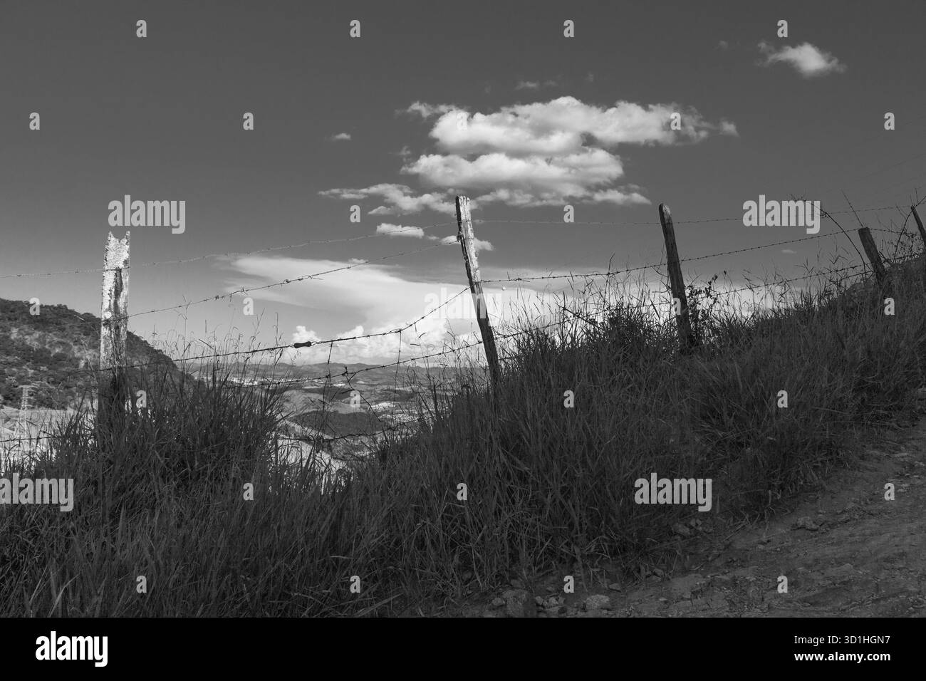 Paesaggio rurale bianco e nero con recinzione a filo spinato e cielo nuvoloso, solitudine, minimalismo, bellezza senza tempo della campagna di Minas Gerais Brasile Foto Stock