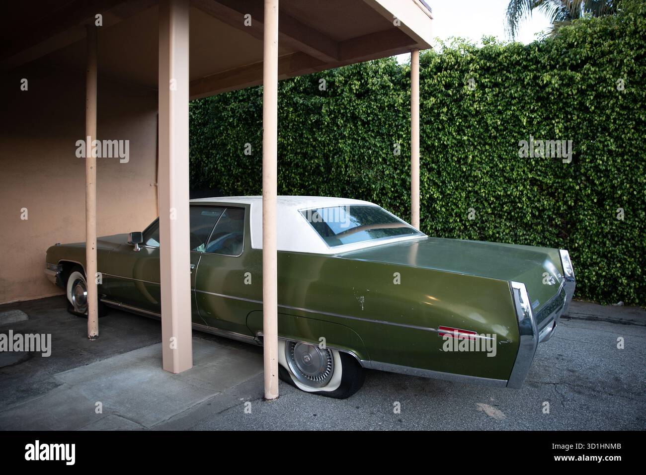 Classica Cadillac verde oliva, probabilmente una Coupe DeVille dall'inizio alla metà degli anni '1970 parcheggiato nel parcheggio dell'edificio residenziale Foto Stock