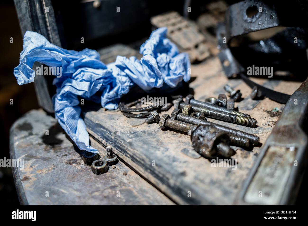 Superficie dell'officina sporca con bulloni e utensili sparsi che rappresentano la riparazione meccanica, la manutenzione industriale e la cura artigianale nella manutenzione dei macchinari Foto Stock