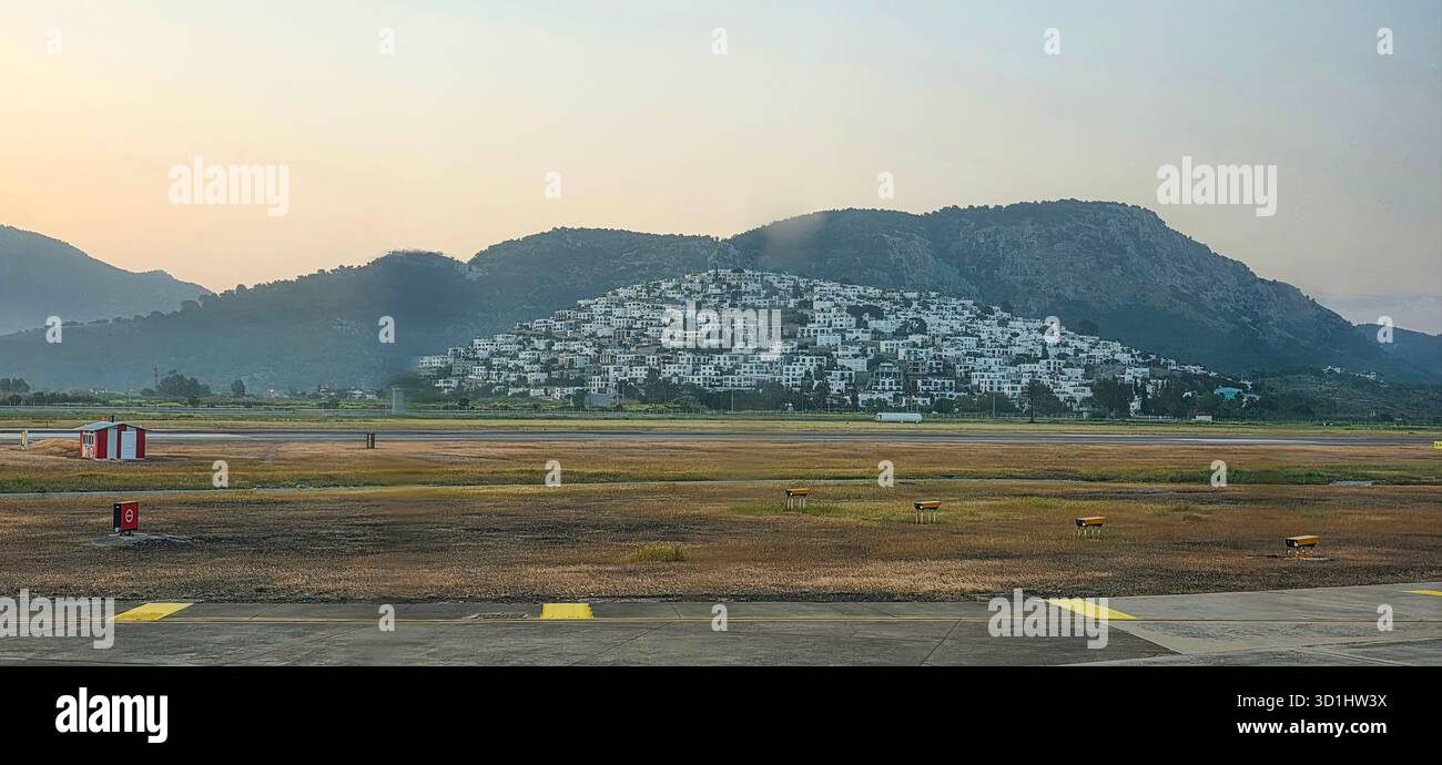 Doloman, Turchia - 25 aprile 2025: Pittoresco villaggio collinare con edifici bianchi sullo sfondo di una montagna. - Immagine stock catturata con smartphone