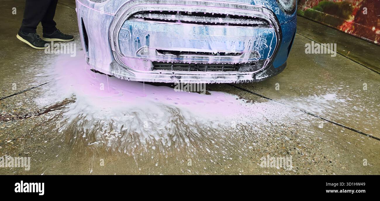 Berlino, Germania - 18 maggio 2025: L'auto viene lavata con schiuma e acqua sul marciapiede in un ambiente esterno. - Immagine stock catturata con smartphone
