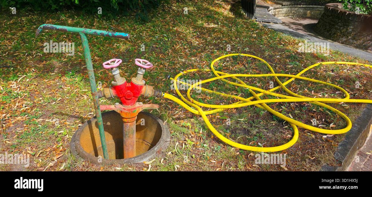 La valvola di alimentazione dell'acqua è caratterizzata da tubi colorati su terreni erbosi illuminati dalla luce del sole. - Immagine stock catturata con smartphone