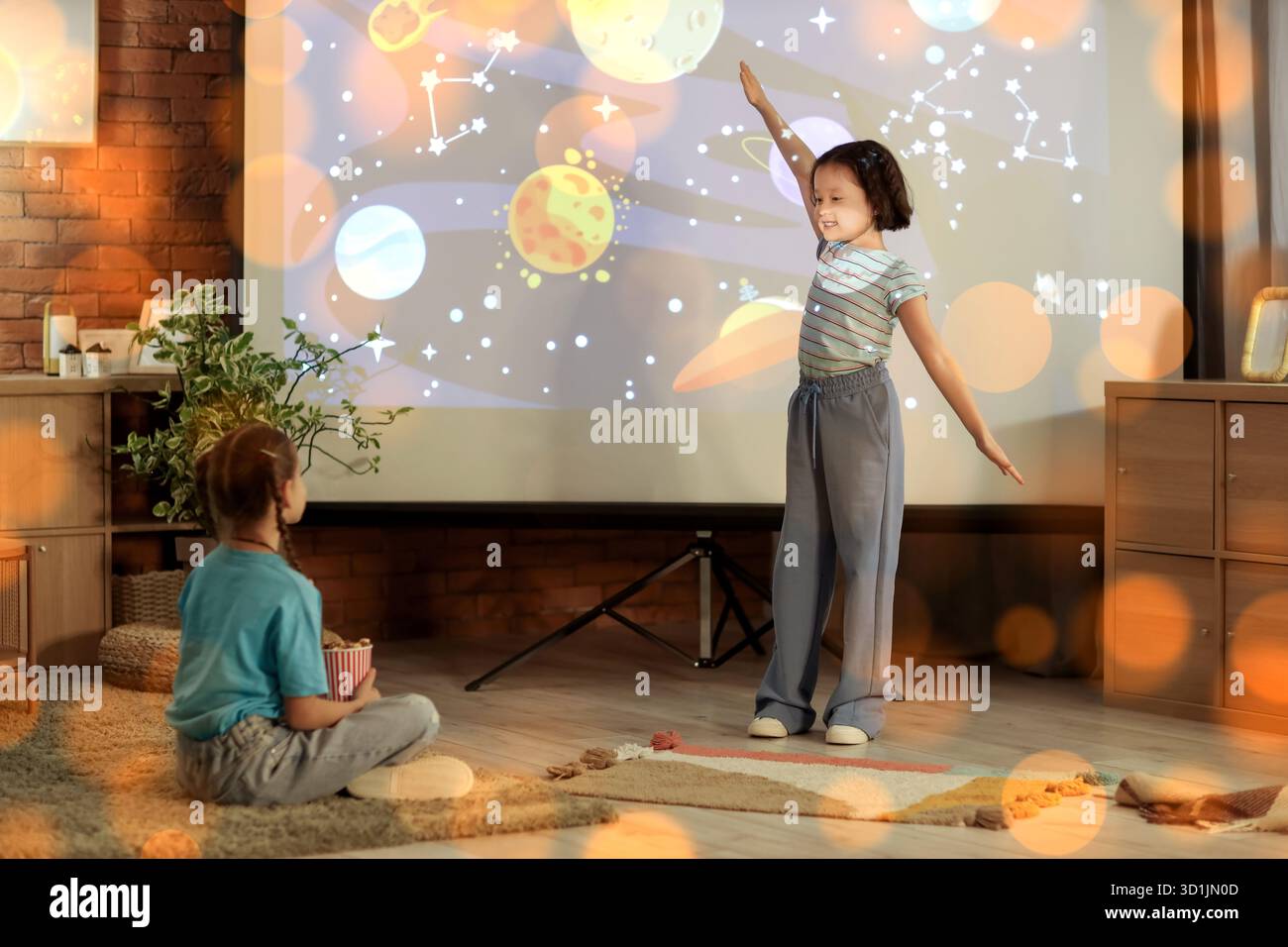 Ragazze carine che guardano i cartoni animati sullo schermo del proiettore a casa la sera Foto Stock