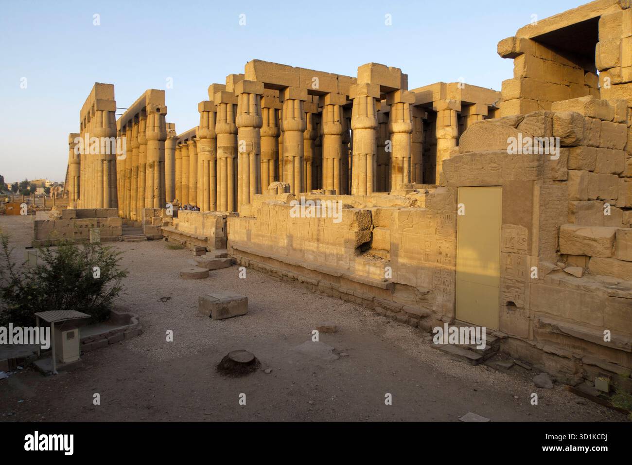 Antiche colonne in pietra del Tempio di Luxor illuminate dalla calda luce del sole in Egitto con persone che camminano per il sito archeologico, l'Egitto Foto Stock