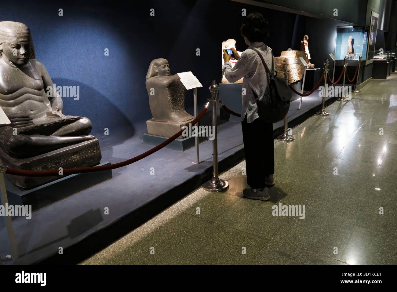 Visitatore che fotografa antiche sculture in pietra esposte dietro le corde al Museo di Luxor, in Egitto Foto Stock