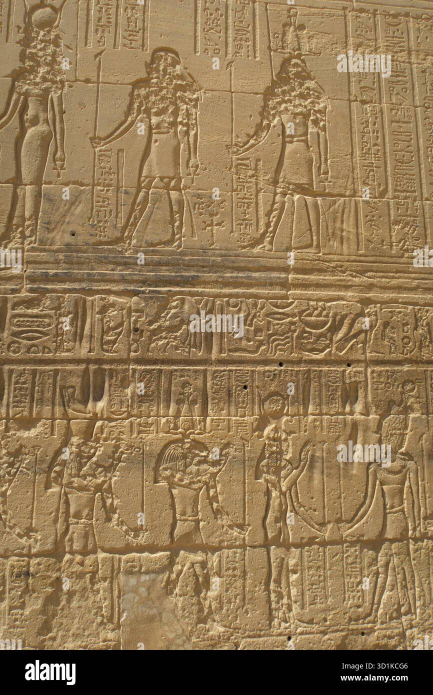 Antiche pareti in pietra egiziane che mostrano geroglifici e figure in pose cerimoniali e religiose presso il Tempio di Edfu Foto Stock
