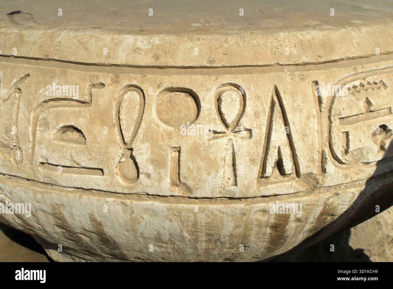 Primo piano dell'antico manufatto in pietra egiziana con dettagliate incisioni geroglifiche su una superficie curva Foto Stock