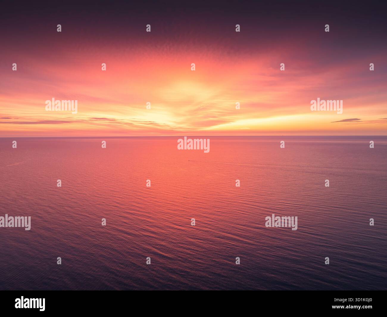 Vibrante e spettacolare tramonto sul mare o ammira l'alba sulle calme acque dell'oceano al tramonto con la superficie riflettente delle onde rosse e arancioni, vista aerea Foto Stock