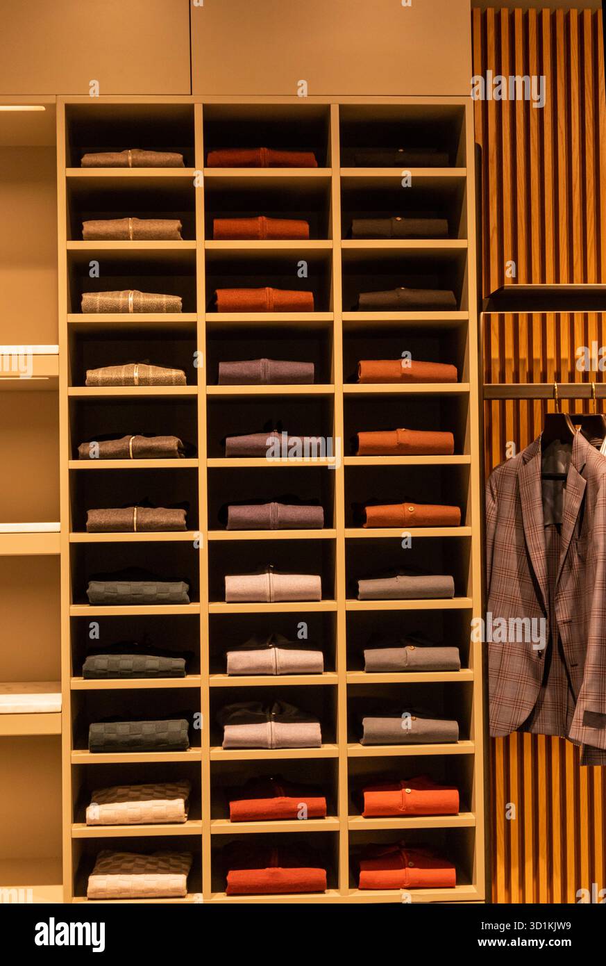 Vista frontale dei ripiani in legno esposti della vetrina con vari maglioni impilati su di essi. vetrina di un padiglione commerciale in un negozio. Campione. Foto Stock