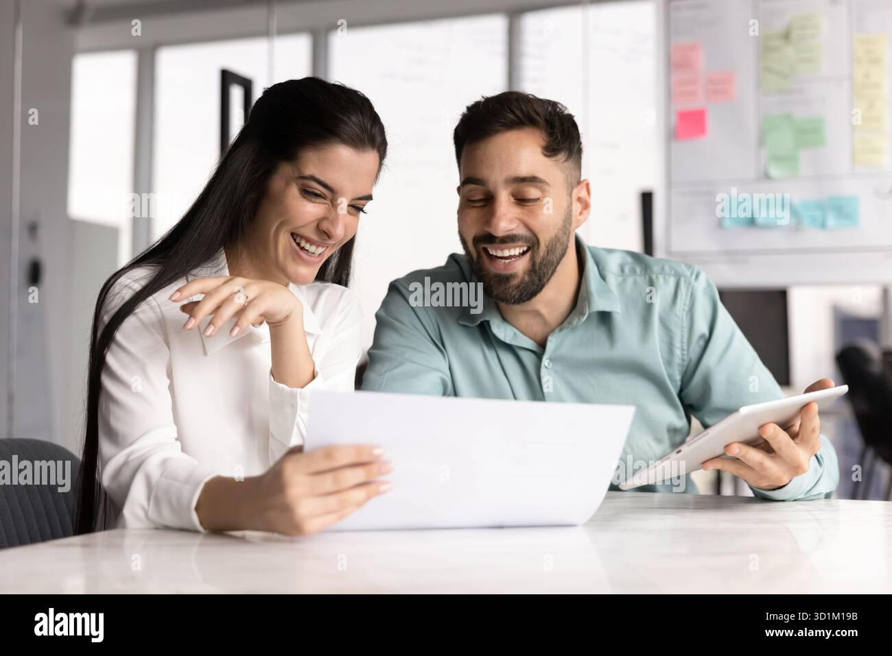 Donna d'affari gioiosa che lavora con un compagno di squadra maschile nell'ufficio Agile Foto Stock