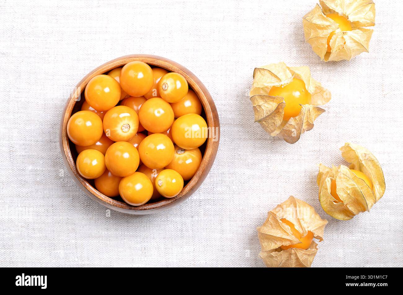 Goldenberries, arachidi peruviane, in una ciotola di legno, su lino. Uva spina del capo matura e fresca, detta anche poha, Physalis peruviana. Foto Stock