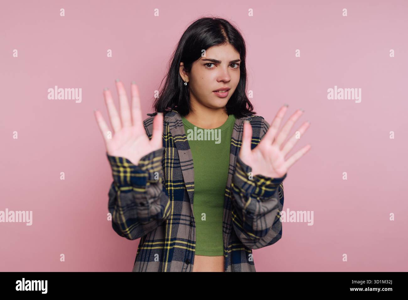 Giovane donna con un'espressione scettica che tiene le mani in alto nel rifiuto. Foto Stock