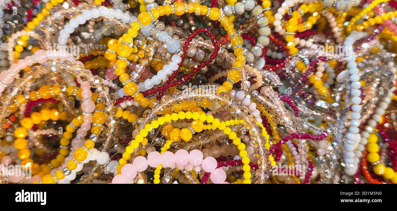 I bracciali colorati con perline sono disposti in un'esposizione artistica, che mostra varie texture e sfumature, creando una scena vibrante e accattivante. Foto Stock