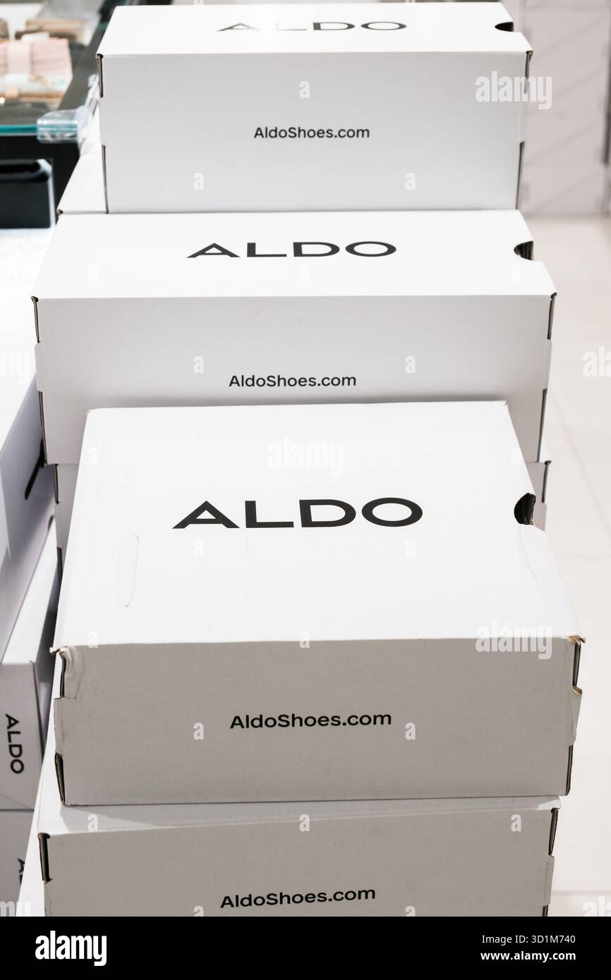 Le scatole per scarpe con marchio ALDO sono sovrapposte in modo prominente, con un semplice colore bianco e un audace logo nero, illuminate da un'illuminazione artificiale brillante. Foto Stock