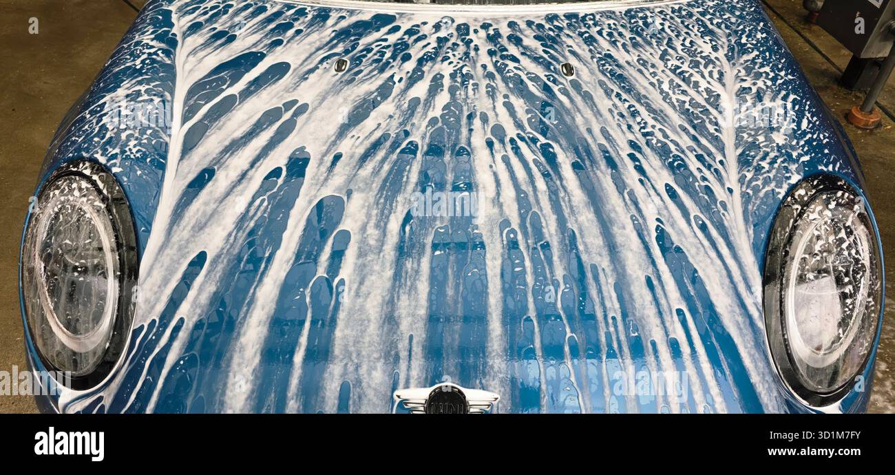 Berlino, Germania - 18 maggio 2025: Il veicolo blu è coperto di sapone durante un lavaggio con un servizio di dettaglio automatico. - Immagine stock catturata con smartphone