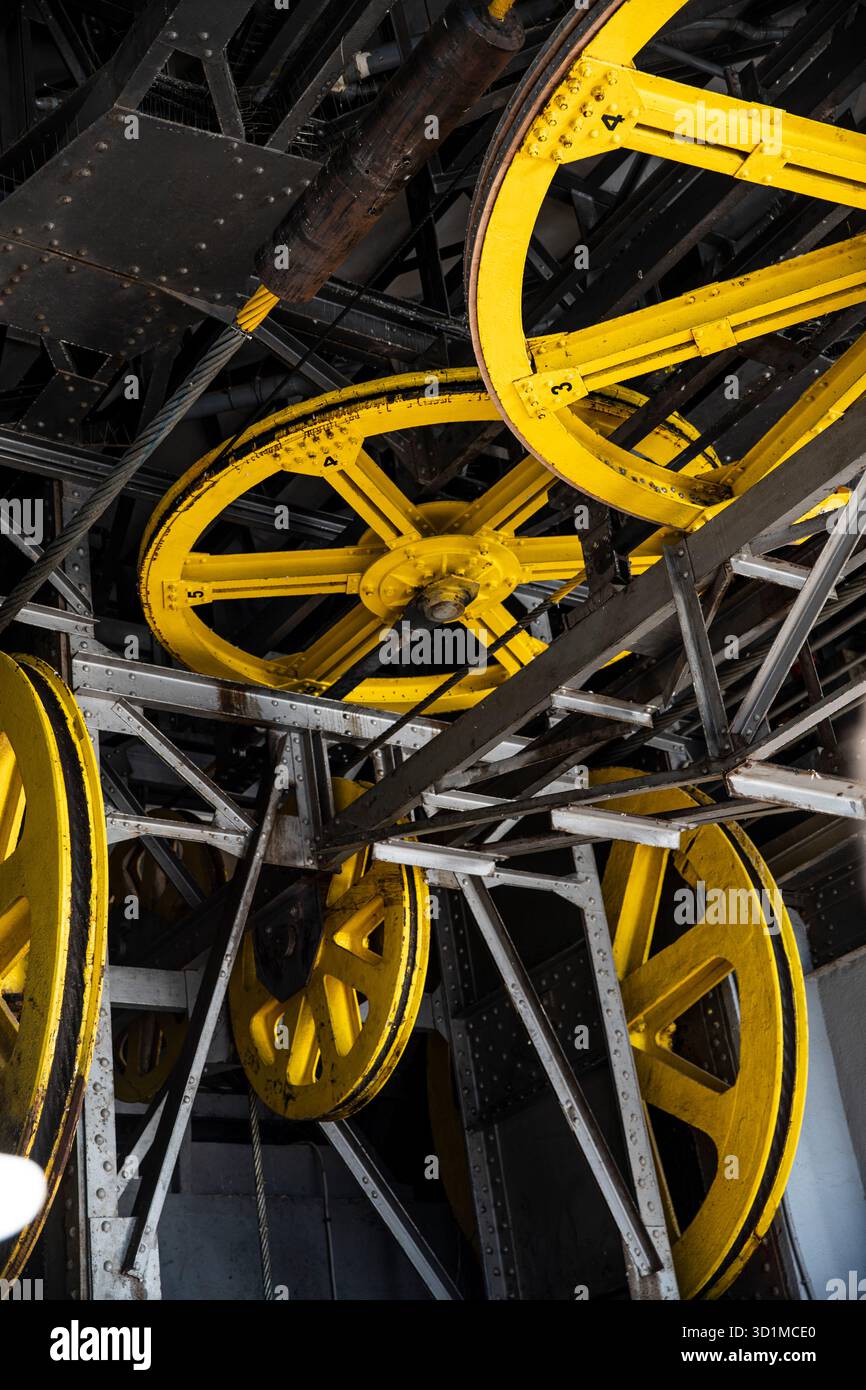 Primo piano di un meccanismo funicolare: Pulegge gialle e travi in acciaio Foto Stock