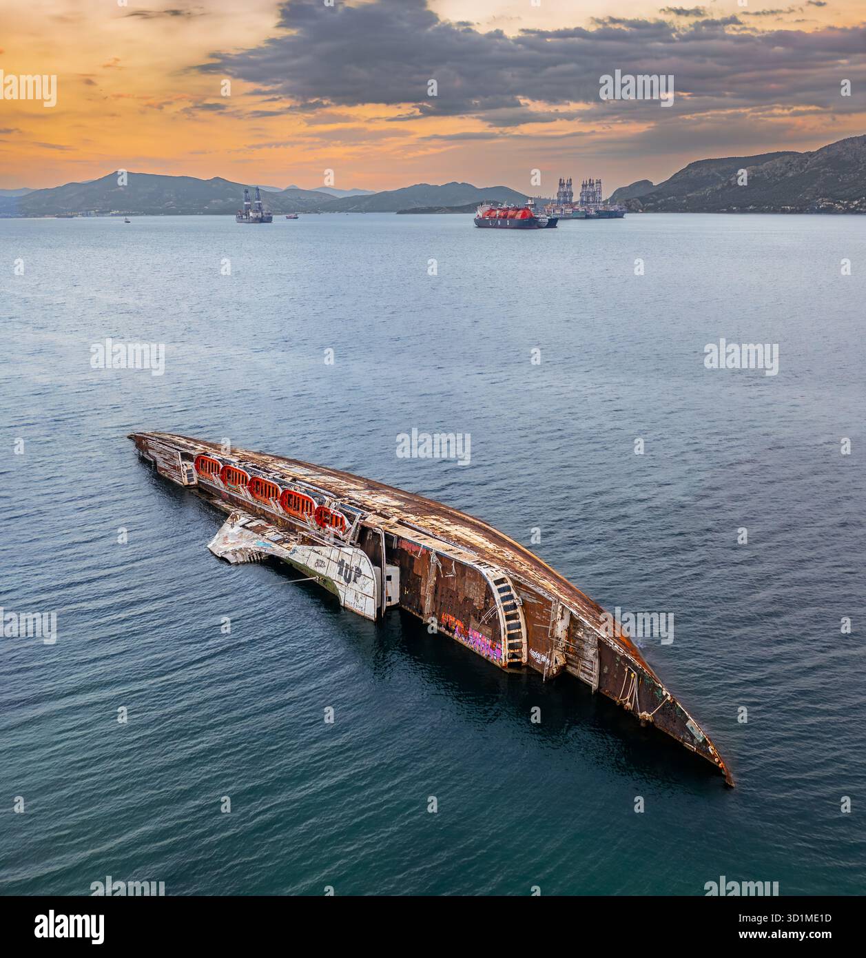 Vista aerea del naufragio che riposa pacificamente nelle tranquille acque blu, con navi e montagne lontane sotto un vibrante cielo al tramonto, Elef Foto Stock