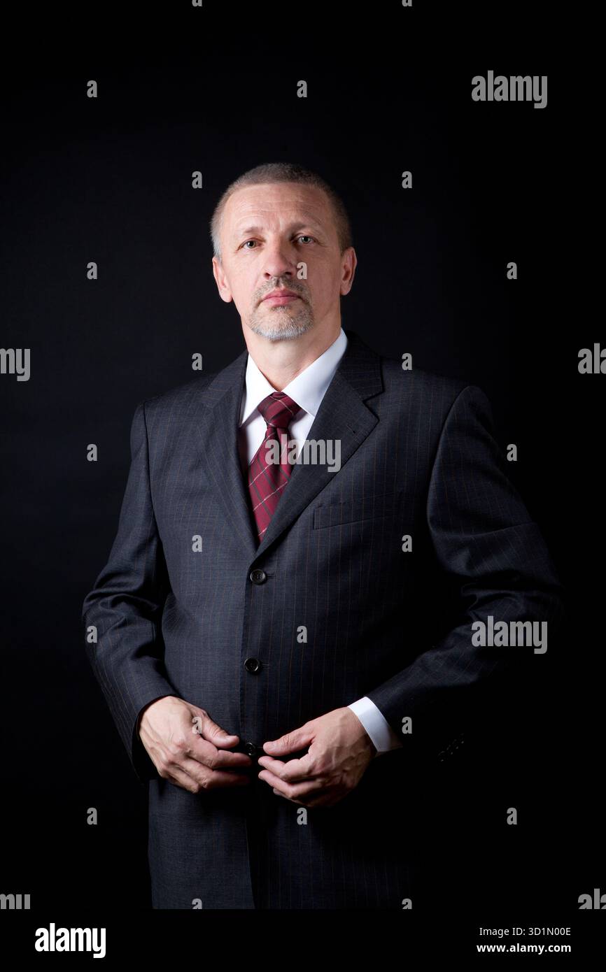 Imprenditore maturo tenendo le mani sul suo vestito nero Foto Stock