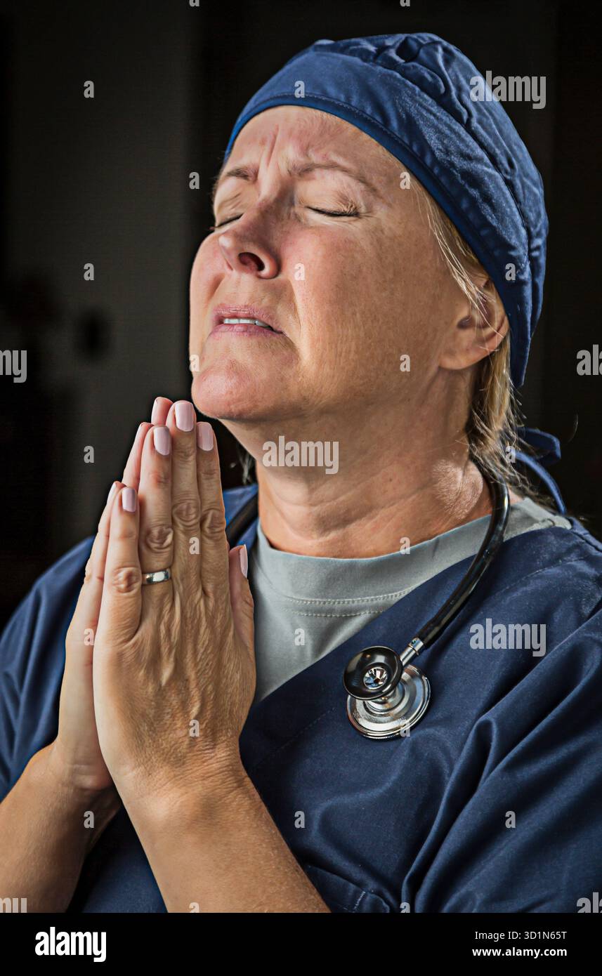Supplicazione di Dottore o infermiera donna in preghiera Foto Stock