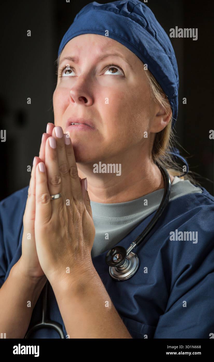 Supplicazione di Dottore o infermiera donna in preghiera Foto Stock