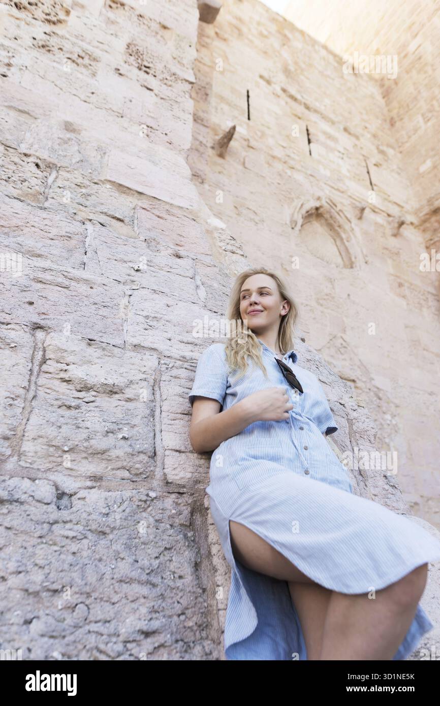 Foto di una bella donna bionda contro il muro rustico della chiesa in Francia a Marsiglia Foto Stock