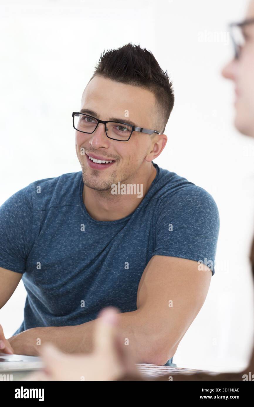 Ritratto di un giovane uomo d'affari in abiti casual presso un moderno ufficio di avvio, che lavora su un computer portatile Foto Stock