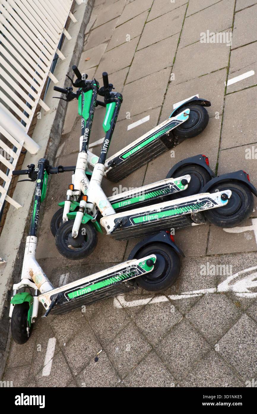 Tre scooter elettrici a noleggio pubblico che si trovano su un marciapiede della città Foto Stock