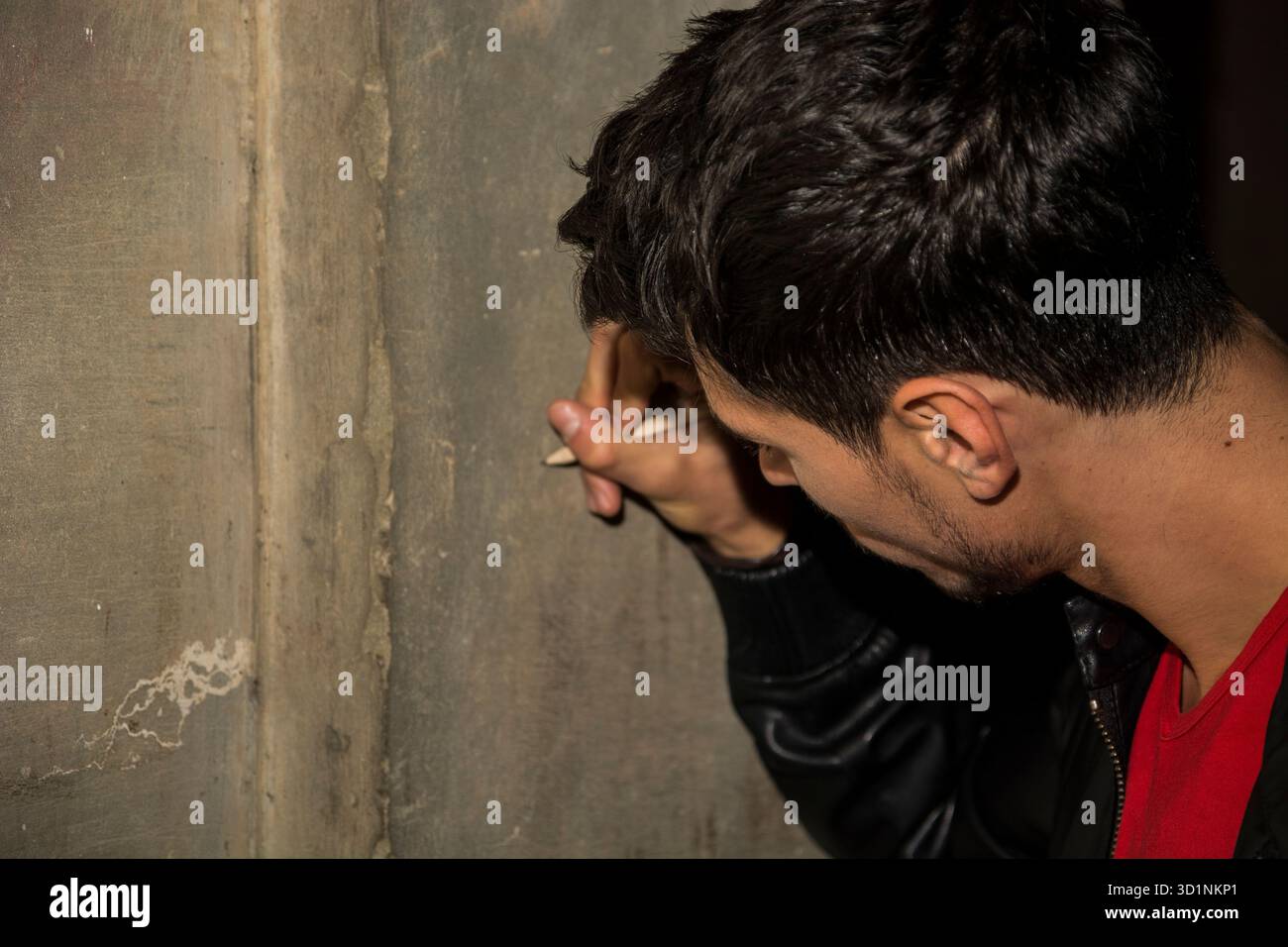 Primo piano di un giovane che scrive su un muro di pietra con una matita Foto Stock
