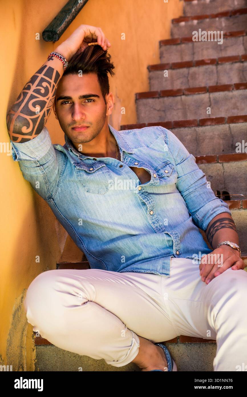 Bel uomo seduto sulle scale mentre guardando la fotocamera Foto Stock