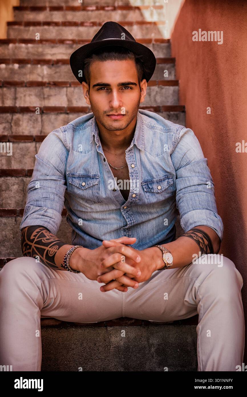 Bel uomo seduto sulle scale mentre guardando la fotocamera Foto Stock