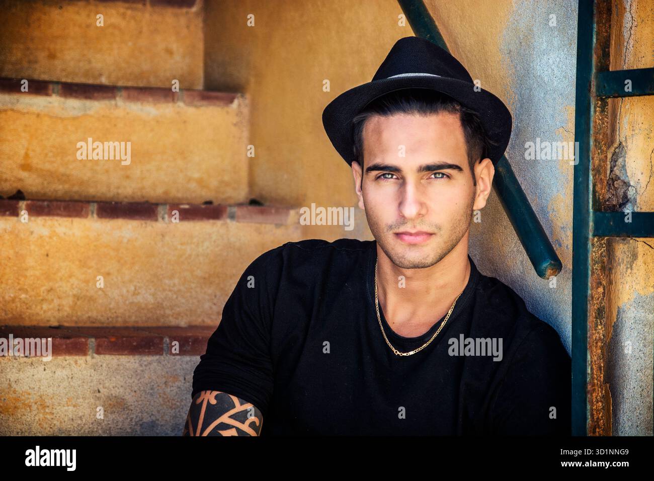 Bel uomo seduto sulle scale mentre guardando la fotocamera Foto Stock