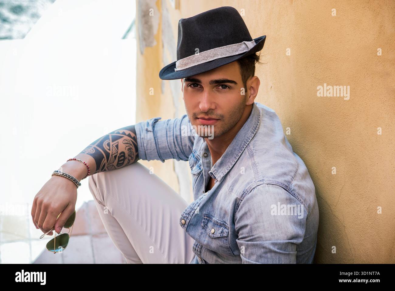 Bel uomo seduto sulle scale mentre guardando la fotocamera Foto Stock